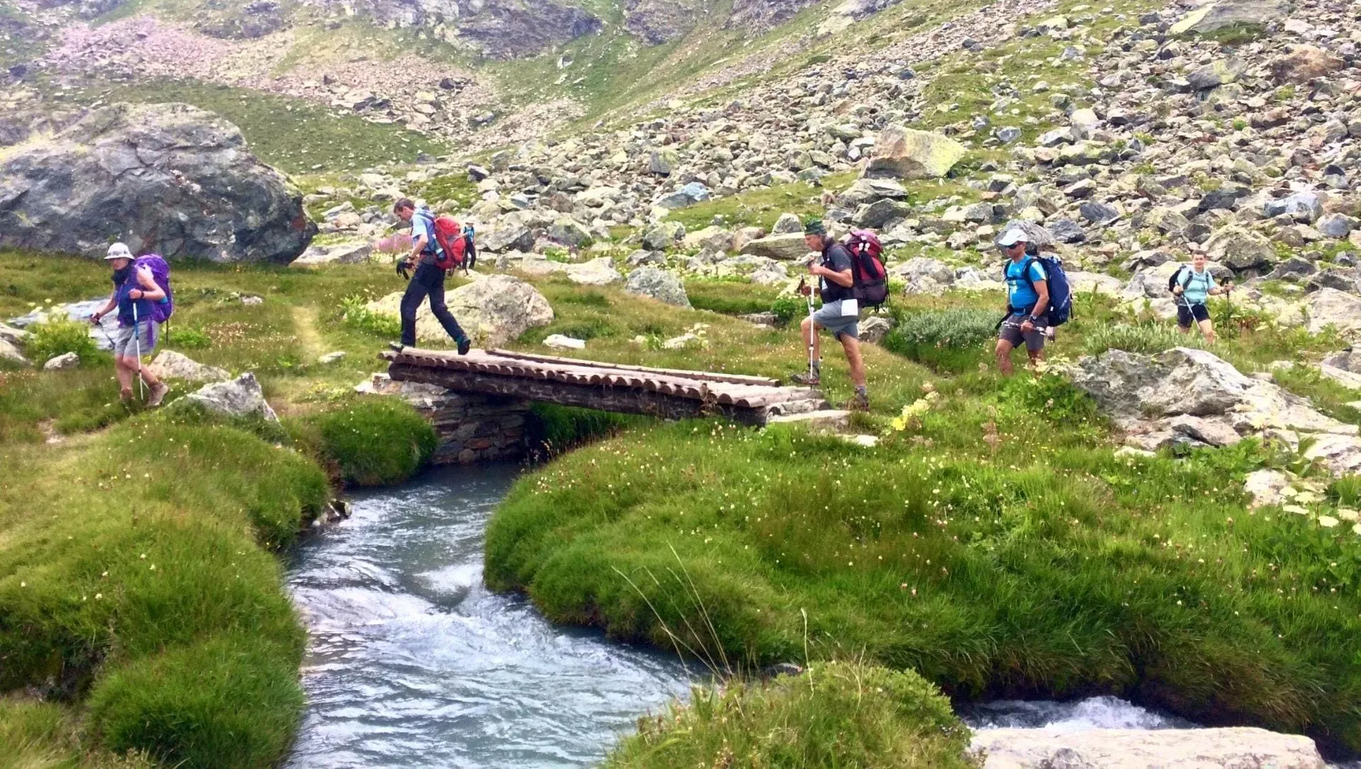 Groupe De Randonneurs Traversant Un Petit Pont De Bois Sur Une Riviere Pendant Le Tour Des Geants C Laurent Comte - Italie © Laurent Comte