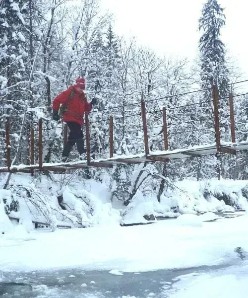 Randonneur traversant un pont enneigé sur la rivière Subersach - Vorarlberg - Autriche © Raymond Chabanier