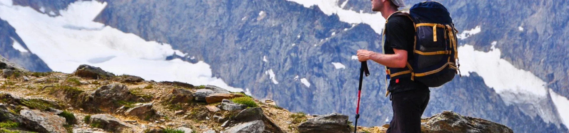Randonneur avec sac a dos et batons face aux sommets enneiges - Alpes