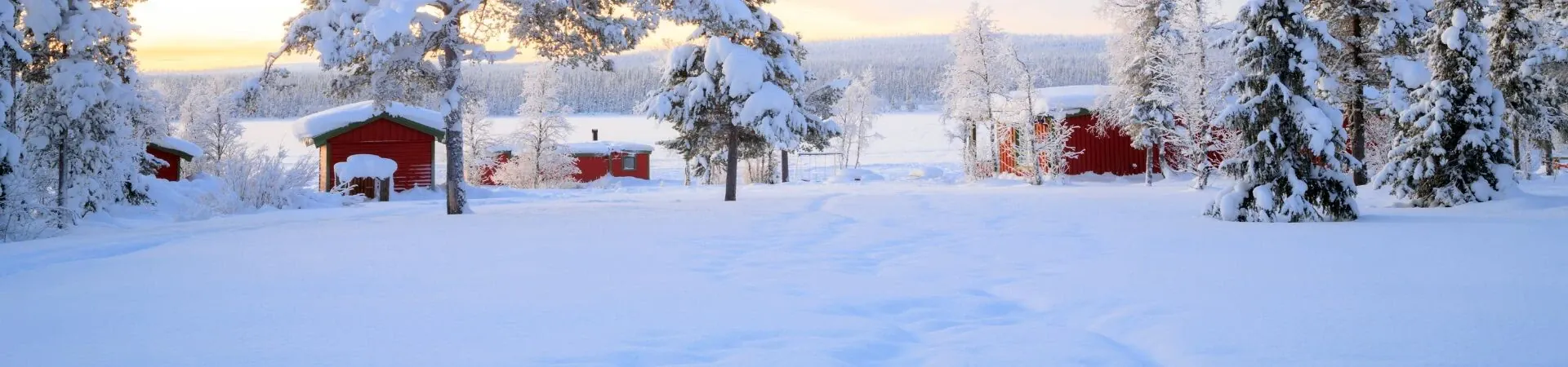 Chalets rouges et sapins enneiges au coucher de soleil - Laponie scandinave